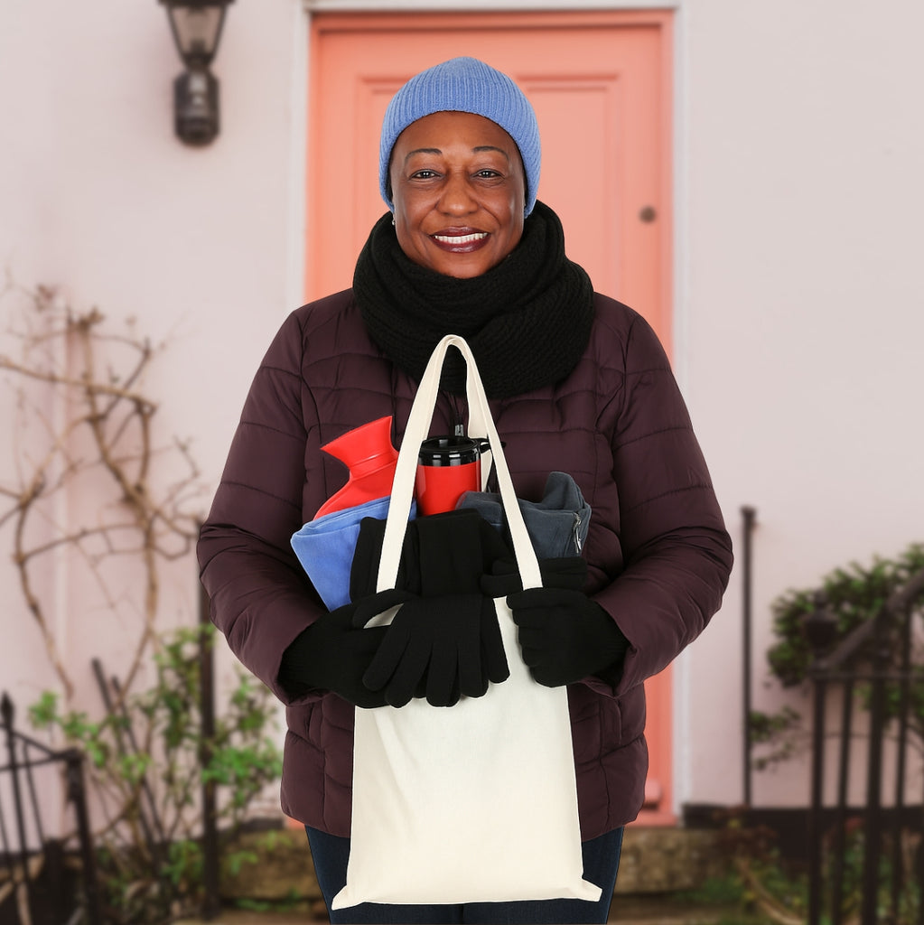 Person holding a reusable tote bag with  winter warm pack in front of a pink door.